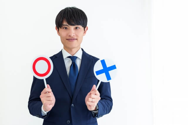 〇×のサインを持つ男性